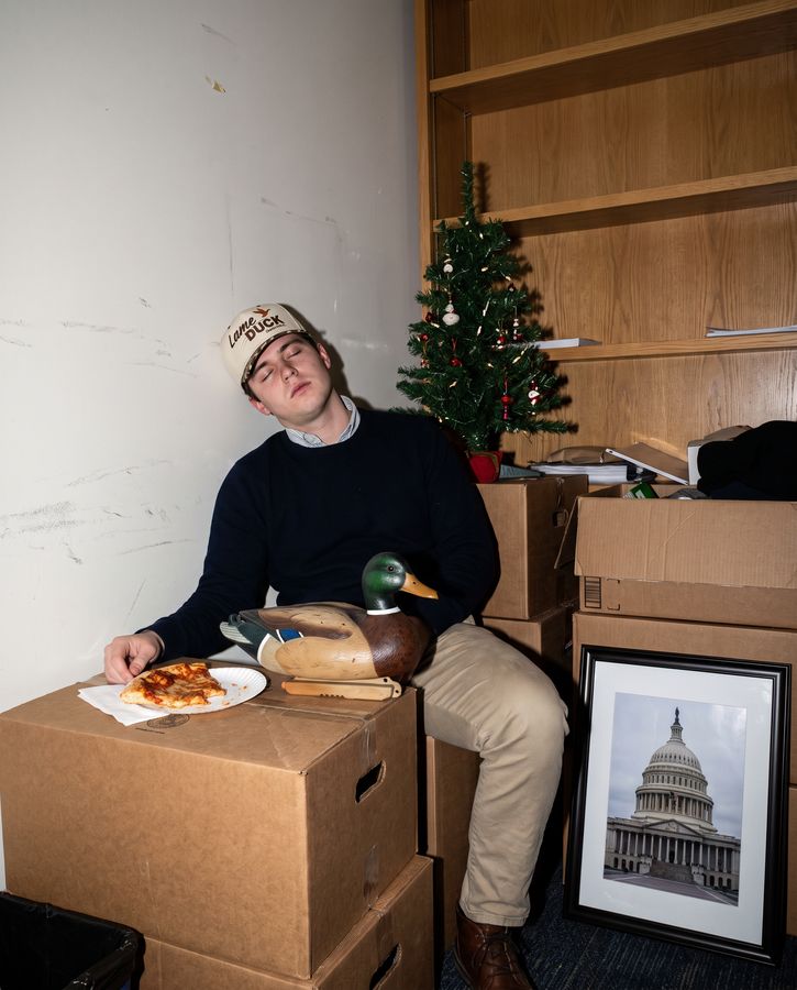 A staffer asleep on moving boxes with a duck decoy, wearing the Lame Duck cap
