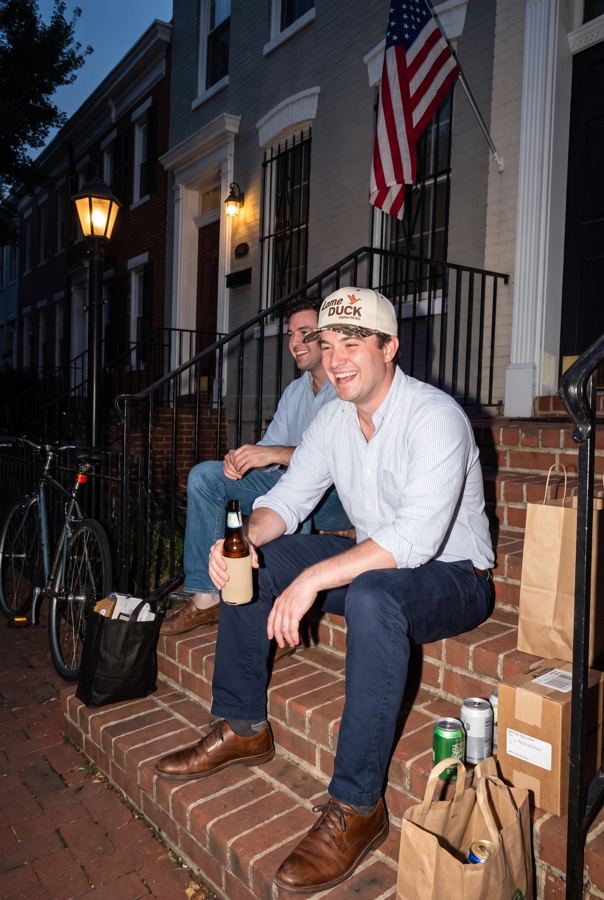Two friends on a rowhouse stoop at dusk